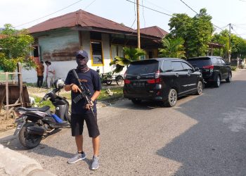 Salah seorang petugas berjaga-jaga dengan senjata lengkap saat aksi penggeledahan Densus 88 di rumah salah seorang warga Kota Padang (ist)