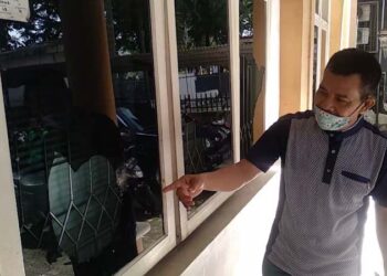 Ketua Komite Olahraga Nasional Indonesia (KONI) Sumatra Barat (Sumbar) Syaiful menunjukkan salah satu kaca jendela kantornya yang dirusak. (Foto: Irwanda)