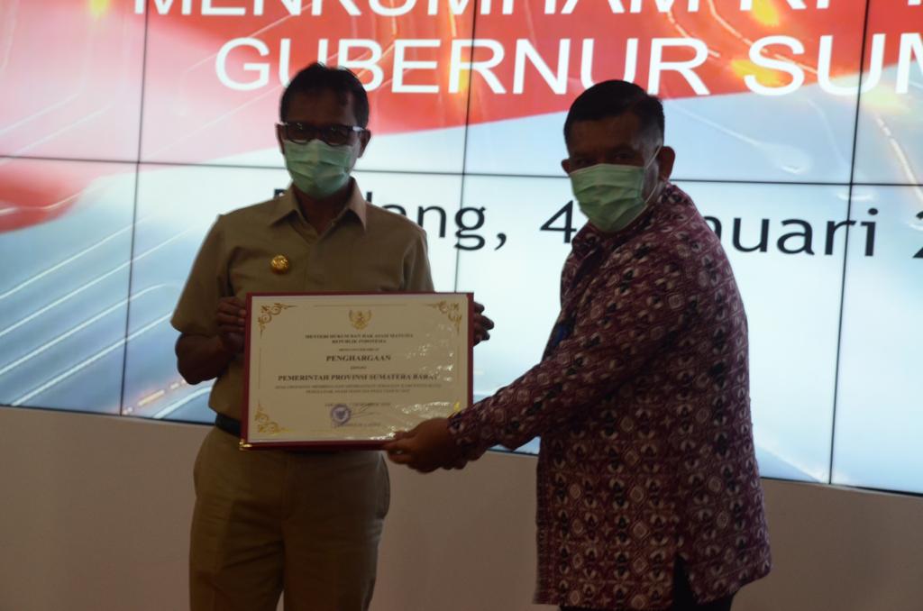 Kepala Kanwil Kemenkumham Sumbar, R Andika Dwi Prasetya menyerahkan penghargaan kepada Gubernur Sumbar Irwan Prayitno lantaran terpilih sebagai provinsi peduli HAM. (Foto: Irwanda/Langgam.id)