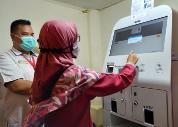 Salah seorang warga sedang menggunakan mesin Anjungan Dukcapil Mandiri (ADM) milik Disdukcapil Kota Padang. (foto: Diskominfo Kota Padang)