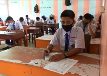 Para siswa MTsN dengan memakai masker, terlihat serius mengerjakan soal-soal ujian. (foto: Ian/langgam.id)