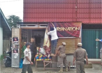 Personel Satpol PP Kota Payakumbuh menertibkan iklan rokok di salah satu warung warga. (foto: Pemko Payakumbuh)