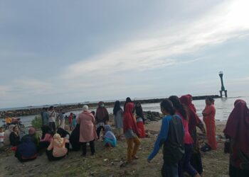 warga menyaksikan proses pencarian nelayan hilang di Muara Surantih, Minggu (13/6/2021). (foto: Debi/langgam.id)