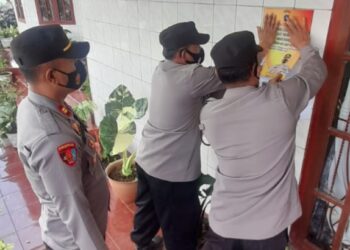 Personel Polsek Danau Kembar Polres Solok pasang stiker pencegahan covid-19 di salah satu rumah warga. (foto: tribratanews.sumbar.polri.go.id)