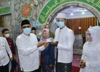 Wali Kota Padang Hendri Septa menyerahkan dokumen kependudukan sebagai bagian dari "Sikado" kepada pasangan pengantin setelah menikah. (Foto: Humas Pemko Padang)