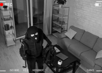 Being Caught. Robber entering house, holding crowbar and looking at CCTV camera, high angle view from above