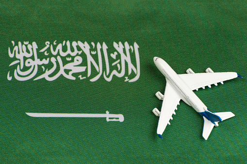 Flag of Saudi Arabia and model airplane. Opening borders after quarantine. Travels.