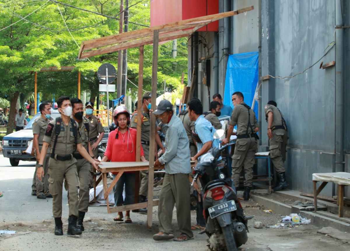 Satpol PP Kota Padang menertibkan lapak pedagang yang berada di kawasan sisi kanan jalan samping pertokoan kompleks Atom Center Padang.