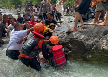 Petugas Basarnas dan warga mengevakuasi salah seorang korban hanyut yang baru ditemukan. (Foto: Dok. Basarnas Padang)