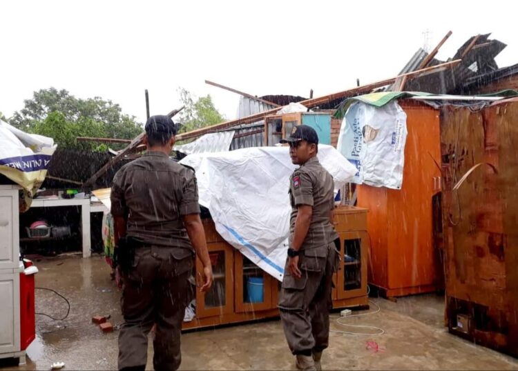 Personil Pol PP Padang membantu membersihkan rumah warga yang rusak akibat angin kencang. [Foto: Humas Pemko Padang]