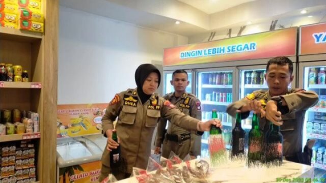 Satpol PP Padang mengamankan sejumlah botol minuman beralkohol dari sebuah mini market di Kecamatan Padang Selatan, Jumat (29/12/2023).